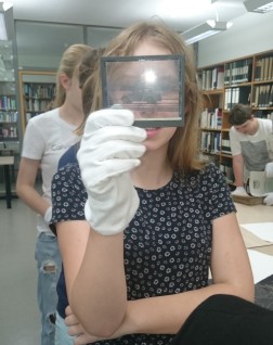 Foto: Mädchen schaut sich ein Glasplattennegativ genauer an